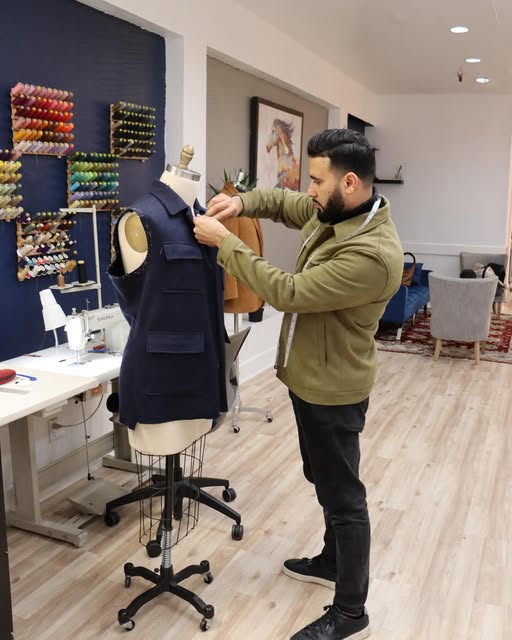 Noori fitting a navy vest on a dress form in the shop